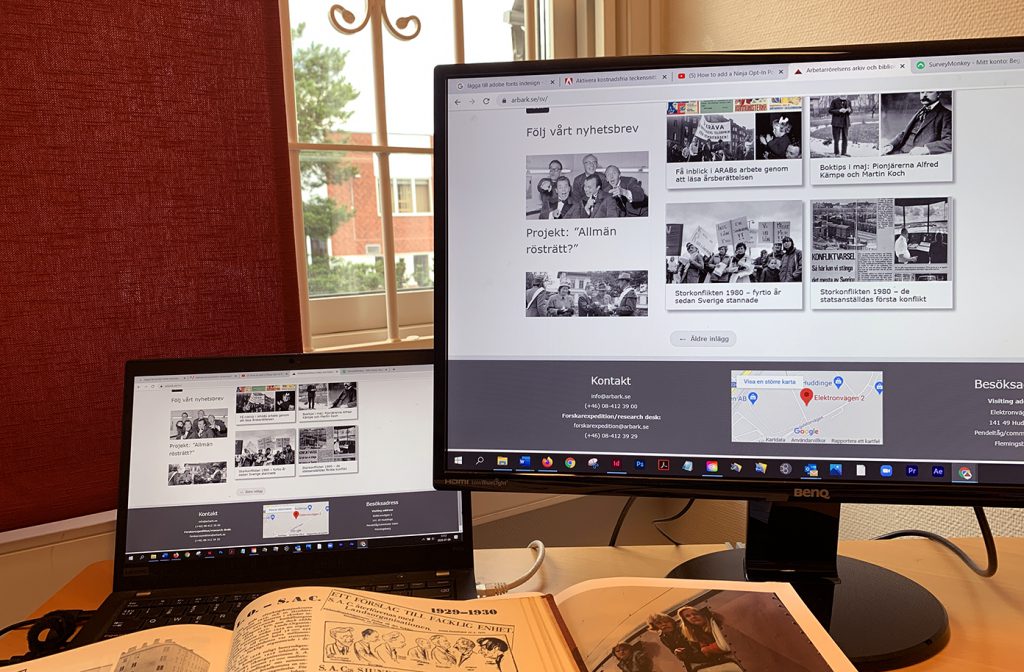 Två datorer med Arbetarrörelsens arkiv och biblioteks webbplats på skärmen. Fönster med röd gardin i bakgrunden.