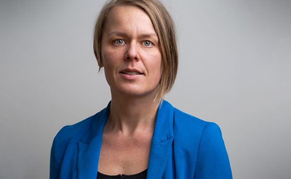 2020 års Rudolf Meidner-pristagare, Desirée Enlund,i blå kavaj mot grå bakgrund.