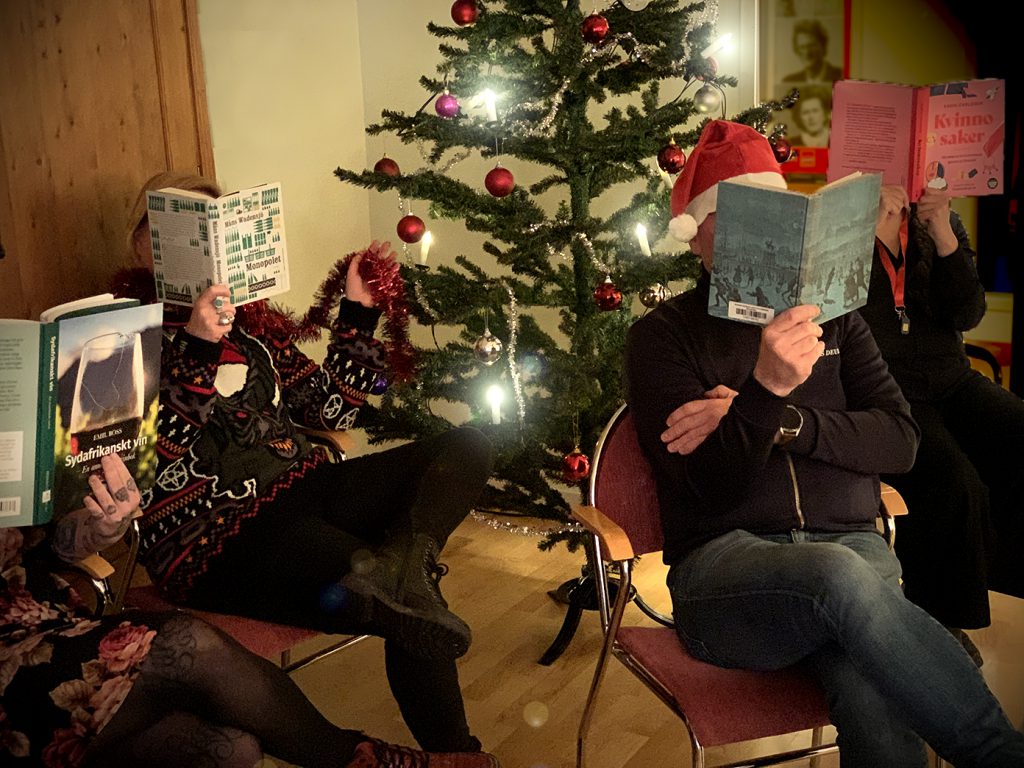 ARABs personal som läser varsin bok framför julgranen.
