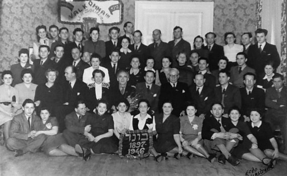 Bundhemmet i Mälarbaden, Torshälla, i mars 1946. På väggen hänger en bild på Hjalmar Branting. På vepan står det "Välkomna!!! Leve socialism". Foto: YIVO