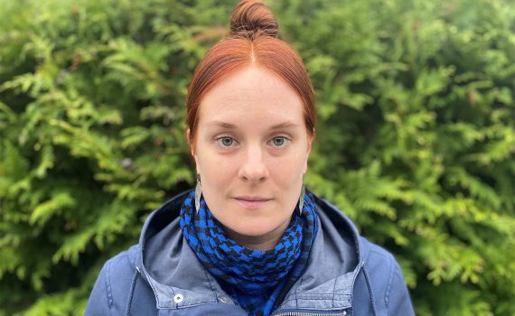 Meidnerpristagaren 2021 Kristin Linderoth med blå jacka mot grön bakgrund.